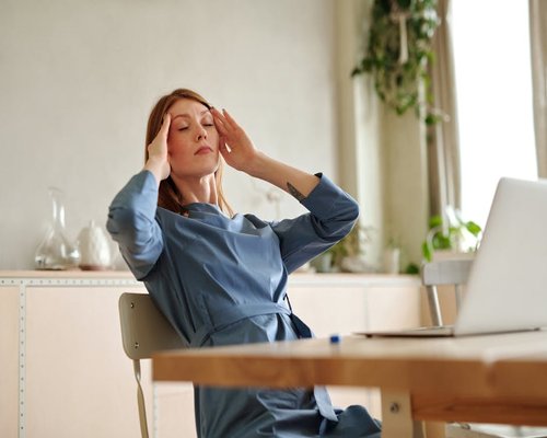 A person sitting at a home office desk looking tired but relaxed